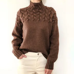 Nahaufnahme eines braunen Rollkragenpullovers mit aufwendigem Zopfmuster und Strickdetails