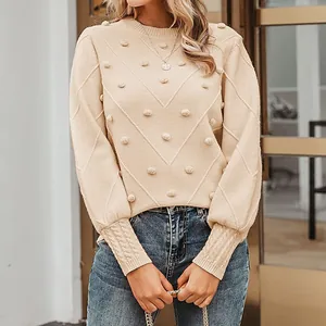 Detailed view of apricot crewneck knit sweater with pom-pom and chevron patterns