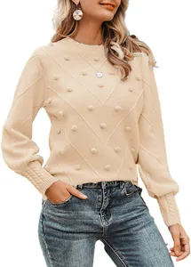Detailed view of women's beige knit sweater with textured pom-poms and diagonal chevron pattern