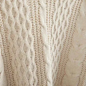 Detaillierte Ansicht der cremefarbenen Zopfmuster-Textur eines Damen-Strickpullovers.