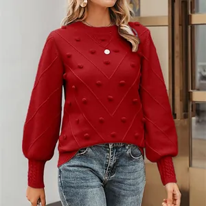 Detail view of a red long-sleeve knitted sweater with pom-poms and elegant crew neck.