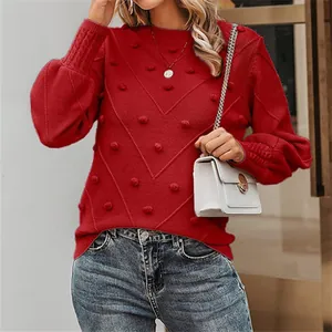 Close-up of red long-sleeve knitted sweater with textured pom-poms and elegant round neck