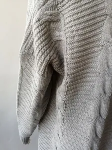 Primer plano que muestra la textura de un cárdigan gris de punto grueso con trenzas