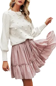 Close-up of white knit texture and decorative pom-poms on an elegant long sleeve sweater