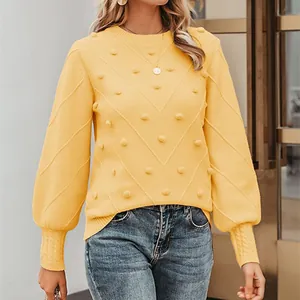 Detail showing the pom-pom accents and chevron texture of the yellow knit sweater.