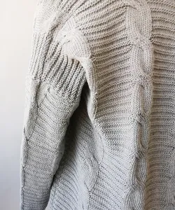Vista detallada de cárdigan gris de punto de ochos con textura gruesa y patrón