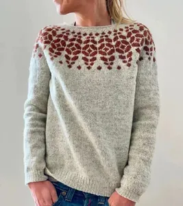 Close-up of a women's light grey knit sweater with a reddish-brown jacquard neck pattern