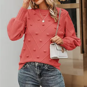 Model wearing coral knit sweater with pom-poms and lantern sleeves in detailed outdoor shot