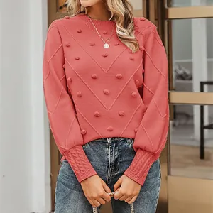 Elegant coral knit sweater featuring pom-pom accents and textured long sleeves detail