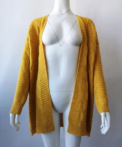 Vista del patrón de ochos amarillo mostaza y la textura de un cárdigan de punto grueso.