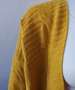Primer plano del intrincado patrón de punto de ochos amarillos en una chaqueta de invierno
