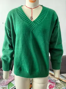 Close-up of the V-neckline and texture of a green knitted pullover on a mannequin form