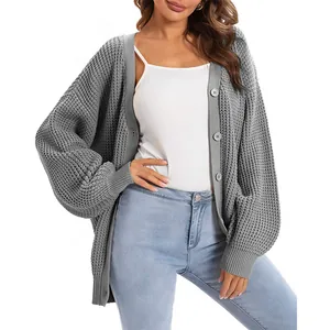 Detailed view of grey oversized knit cardigan featuring chunky texture and front buttons.