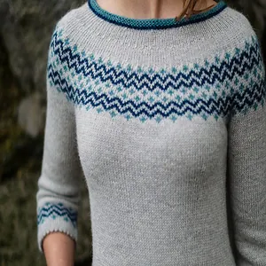 Close-up of women's round neck sweater with blue geometric pattern and knit texture.