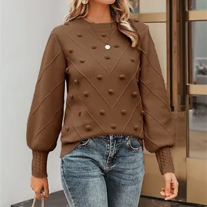 Close-up of brown knit sweater featuring 3D pom-poms and elegant lantern sleeves.