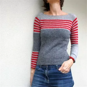 Detail view of a grey and red striped knit sweater on a model in a casual setting
