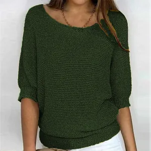Close-up detail of dark green knit top with three-quarter sleeves and soft knit texture