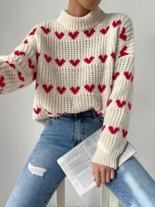 Close-up of a chunky cream knit sweater featuring red heart jacquard patterns on a model