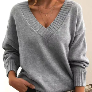 Detail view of a loose grey V-neck knitted sweater with soft texture and ribbed collar