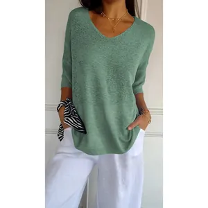 Detail view of the green v-neck knit sweater fabric and relaxed 3/4 sleeve styling