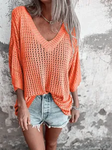 Close-up detail of a bright orange hollow-out knit sweater featuring a stylish V-neck