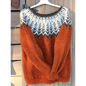Dettaglio di un accogliente maglione in maglia arancio ruggine con elegante motivo nordico.