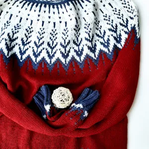 Primo piano di un maglione nordico rosso in maglia con dettagli bianchi e blu scuro eleganti