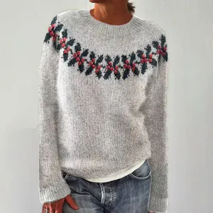 Dettaglio di un maglione grigio in maglia con motivo festivo di agrifoglio e bacche