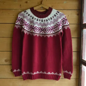 Primo piano di un accogliente maglione bordeaux con intricati motivi nordici Fair Isle.