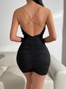 Détail du dos d'une robe moulante noire avec des bretelles croisées en chaîne dorée