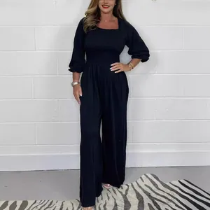 Detail view of black smocked wide-leg jumpsuit with long sleeves and square neck design