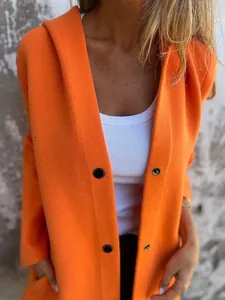 Gros plan d'un cardigan à capuche orange vif avec des boutons-pression noirs en maille.