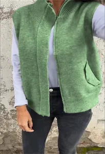 Close-up of the green knitted vest featuring a stand collar and metal front zipper