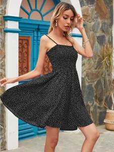 Photo lifestyle en extérieur d'une mini robe noire à pois avec de fines bretelles