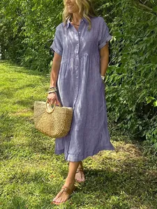 Outdoor lifestyle shot of a woman wearing a blue striped linen shirt dress with straw bag