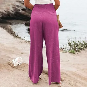 Vue arrière d'un pantalon large fuchsia en lin à taille haute élastique sur la plage.