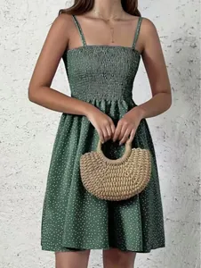 Gros plan d'une mini-robe bohème à pois verts avec un sac à main en paille tressée