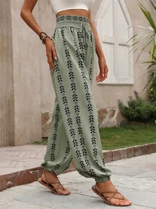 Detailed macro view of sage green geometric print harem pants with smocked elastic waist.