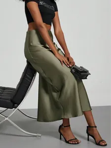Detail shot of an elegant olive green high-waisted satin midi skirt with glossy finish.
