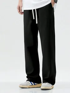 Close-up view of men's loose black wide-leg casual pants with a drawstring waist design.