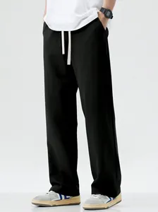 Detail view of men's loose black casual trousers with white drawstring waist