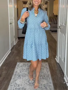 Full body detail of a blue V-neck dress with white diamond pattern worn by woman