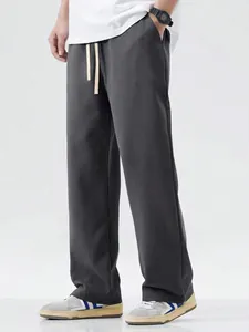 Detail shot of men's loose charcoal drawstring casual pants in a studio setting.