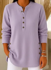 Detailaufnahme der fliederfarbenen Waffelstrickstruktur und Knopfdetails an einem Damenoberteil