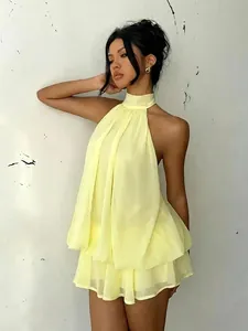 Detail view of a vibrant yellow halter neck backless tiered dress perfect for resort wear