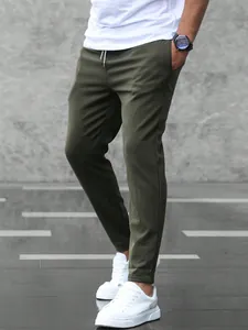 Men's olive green slim fit casual jogger pants shown with white sneakers detail view