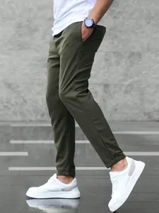 Detailed side view of men's olive green cropped jogger pants styled with white sneakers