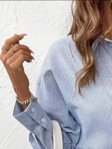 Detailed view of women's blue and white striped button-down shirt with elegant cuffs