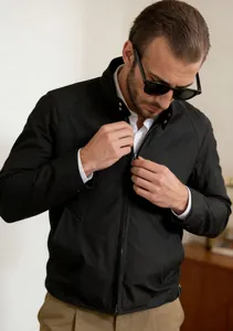 Detailed view of a man adjusting the metallic zipper on a black stand collar jacket