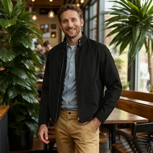 Detail of a man wearing a black minimalist stand collar zipper jacket in a cafe